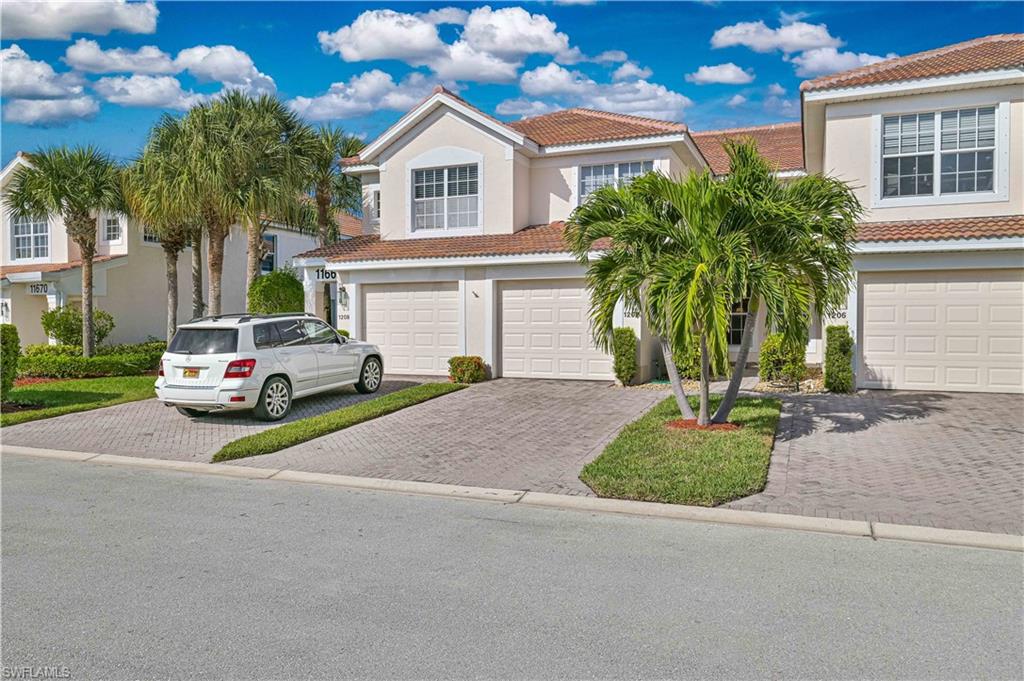 View of front facade featuring a tile roof, decorative driveway, stucco siding, and a garage