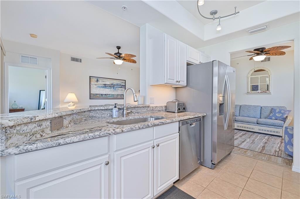 Kitchen featuring ceiling fan, light stone countertops, white cabinets, and appliances with stainless steel finishes