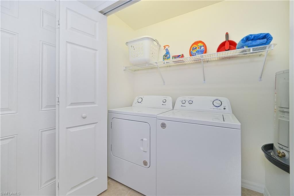 Laundry room featuring washing machine and clothes dryer, light tile patterned floors, and electric water heater