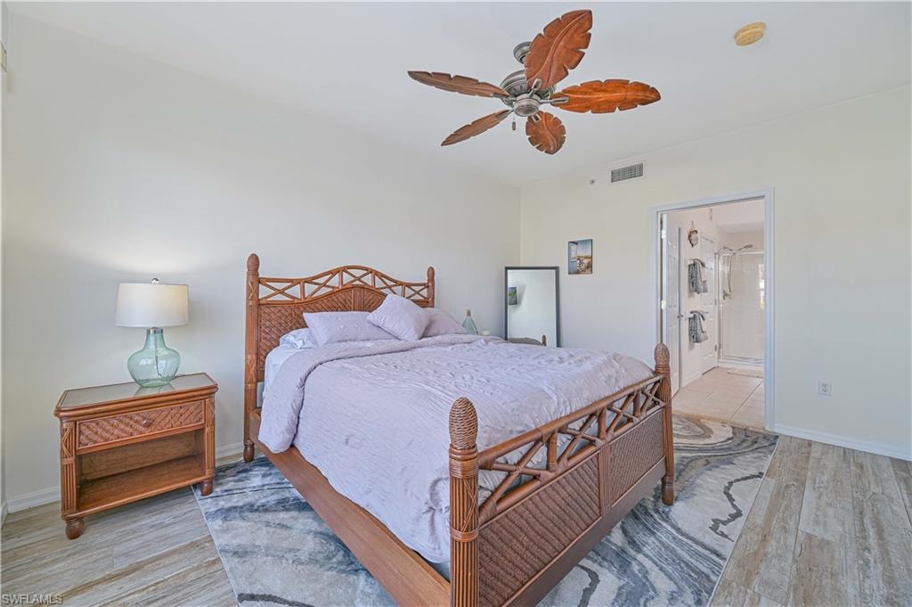 Bedroom with light wood-style floors, ceiling fan, and ensuite bathroom