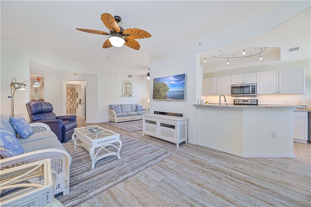 Living area with light wood finished floors and ceiling fan