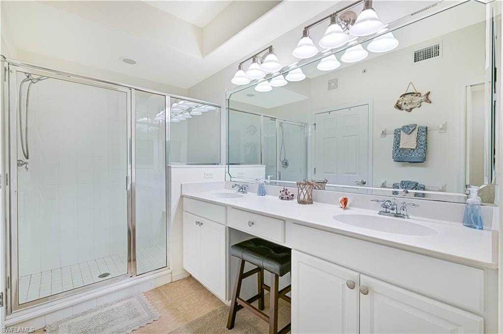 Full bath with double vanity, a stall shower, and light tile patterned flooring