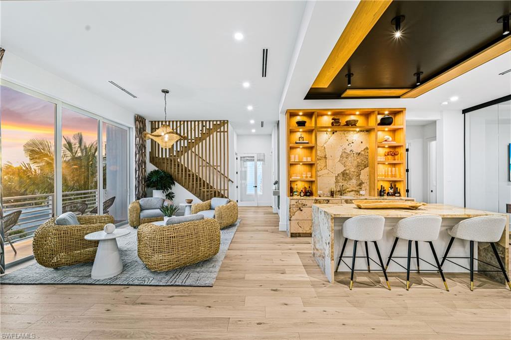 Indoor bar with open shelves, stairway, recessed lighting, light wood finished floors, and light stone counters