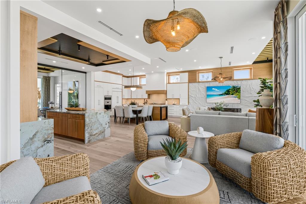 Living area with a tray ceiling, recessed lighting, and light wood-style floors
