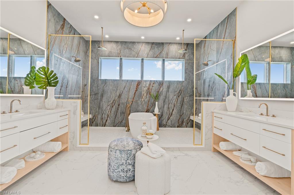 Full bath featuring light marble finish flooring, a marble finish shower, two vanities, recessed lighting, and stone wall