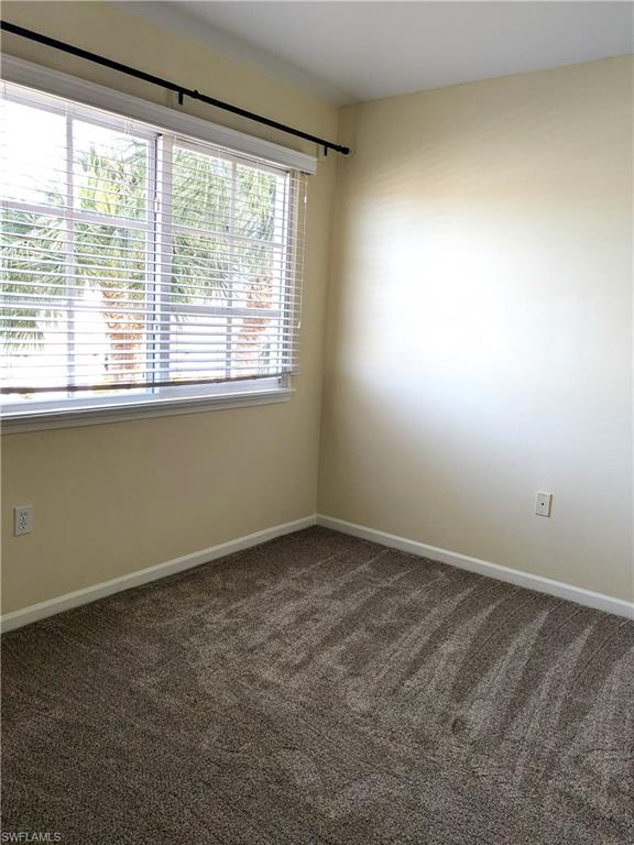 Spare room with dark carpet and baseboards