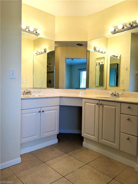 Full bath featuring double vanity and light tile patterned floors