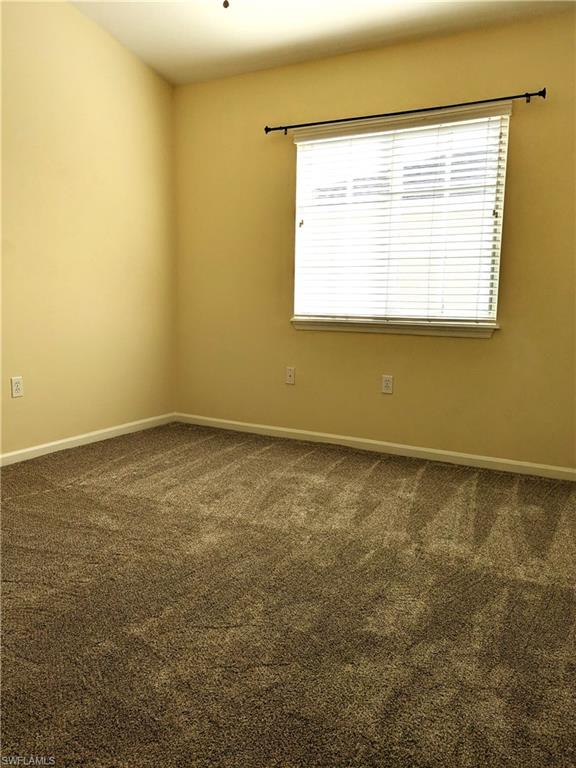 Spare room featuring baseboards and dark colored carpet