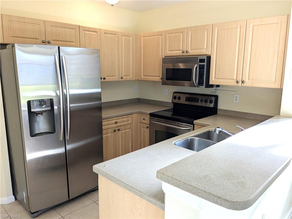 Kitchen featuring stainless steel appliances, a peninsula, light brown cabinets, and light tile patterned floors
