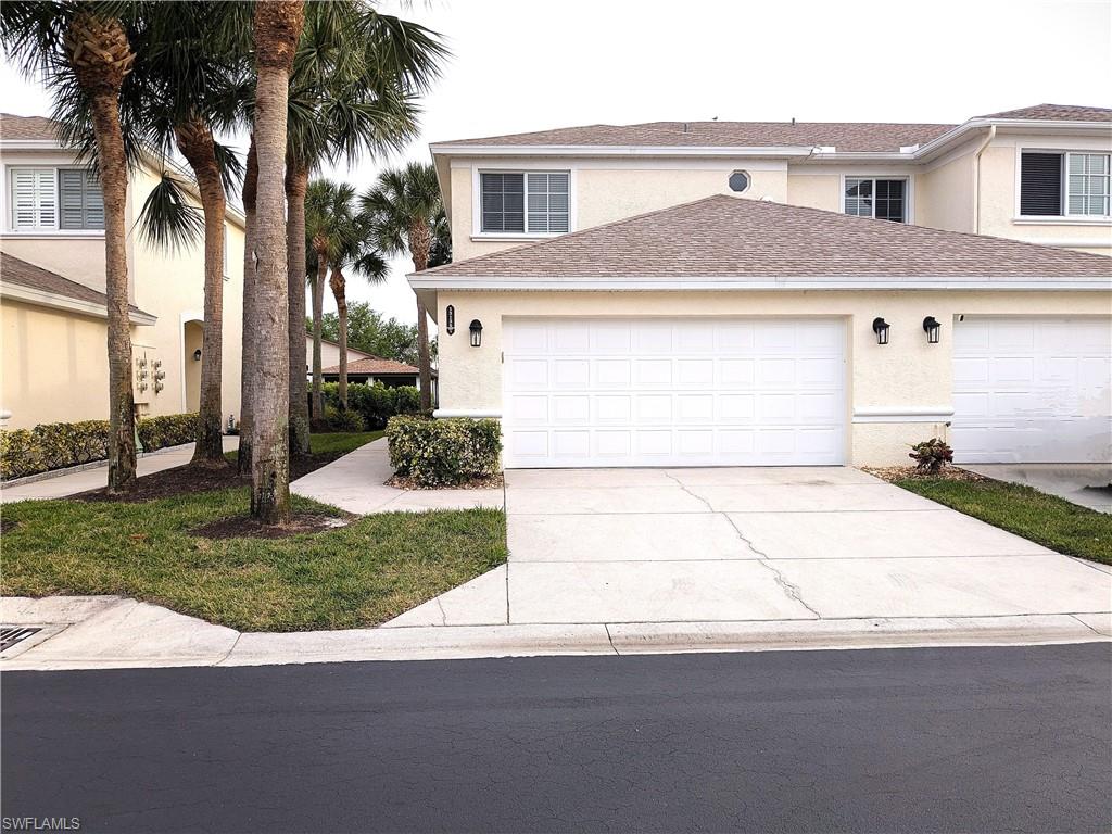 Traditional home with stucco siding, roof with shingles, driveway, and an attached garage