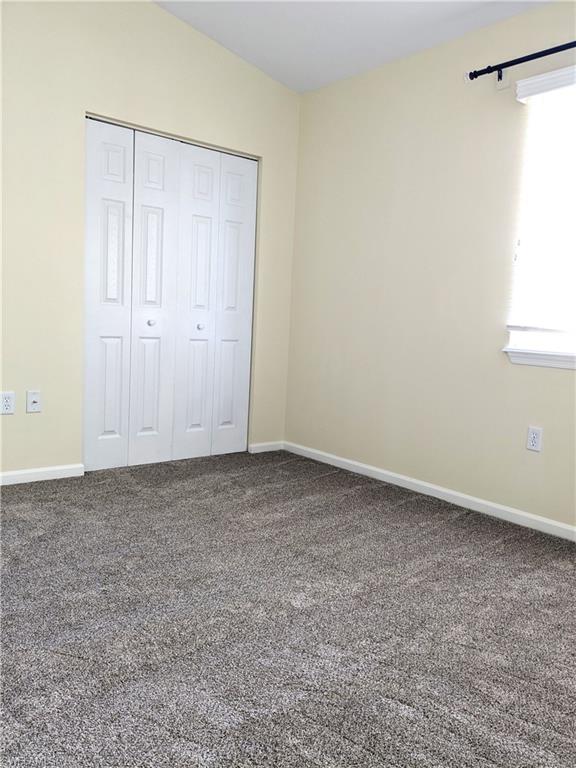 Unfurnished bedroom featuring dark colored carpet and a closet