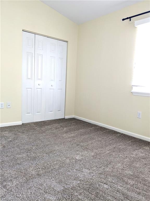 Unfurnished bedroom featuring dark carpet and a closet