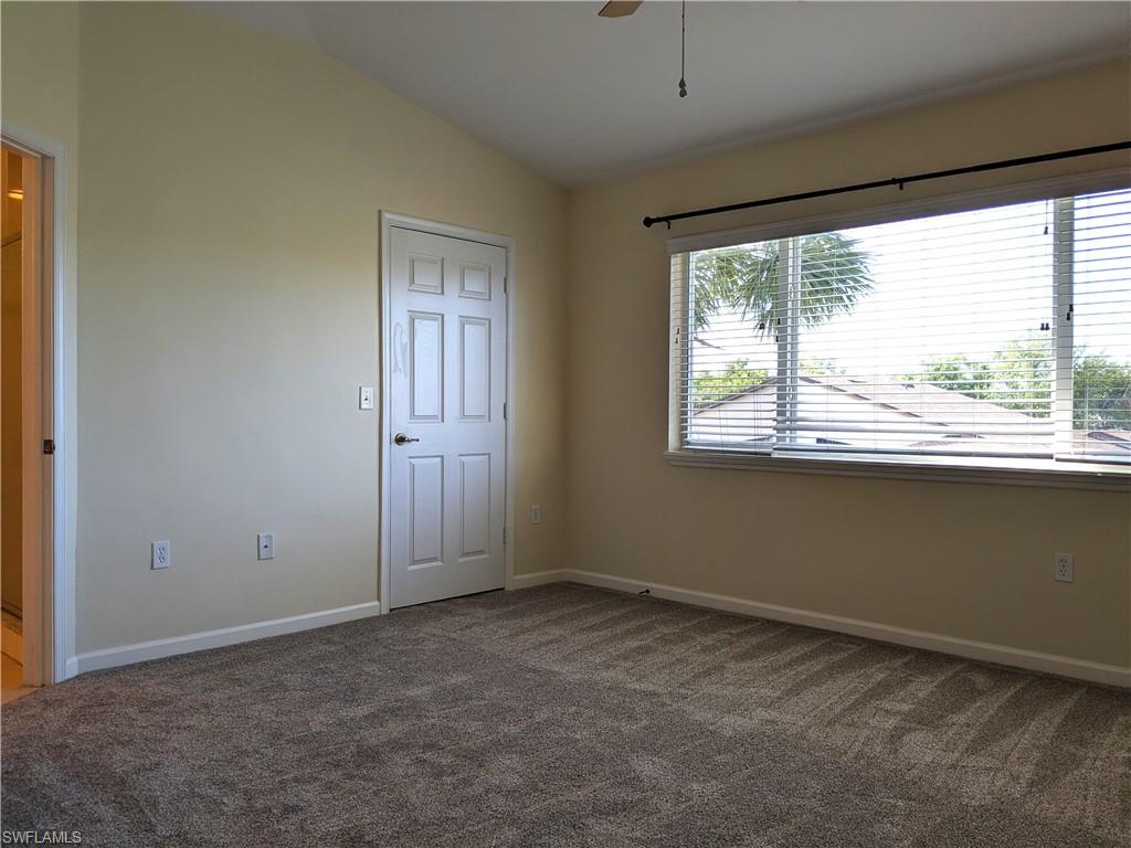 Unfurnished room with vaulted ceiling, dark carpet, and a ceiling fan