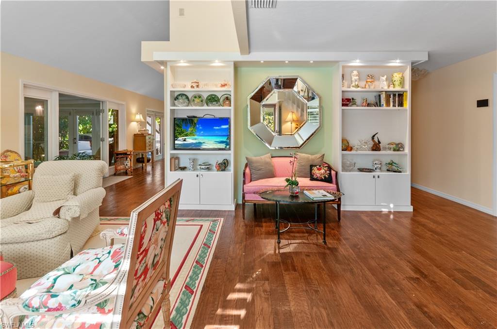 Living area with built in shelves and lofted ceiling, and french doors entry view