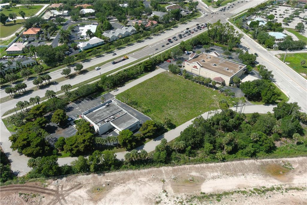 Expansive undeveloped parcel featuring mature perimeter trees, direct road frontage, and proximity to established commercial structures and thoroughfares