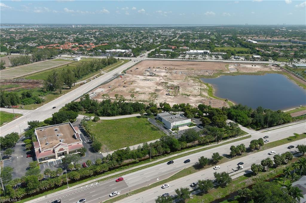 Expansive land parcel featuring direct road frontage, a substantial pond, existing commercial structures, and surrounding natural foliage