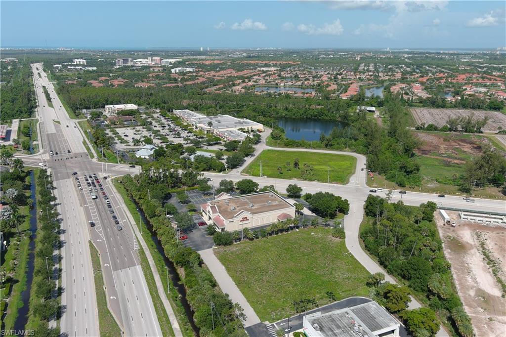 Aerial perspective showcasing expansive commercial and residential areas, featuring multiple roadways, commercial structures, and bodies of water