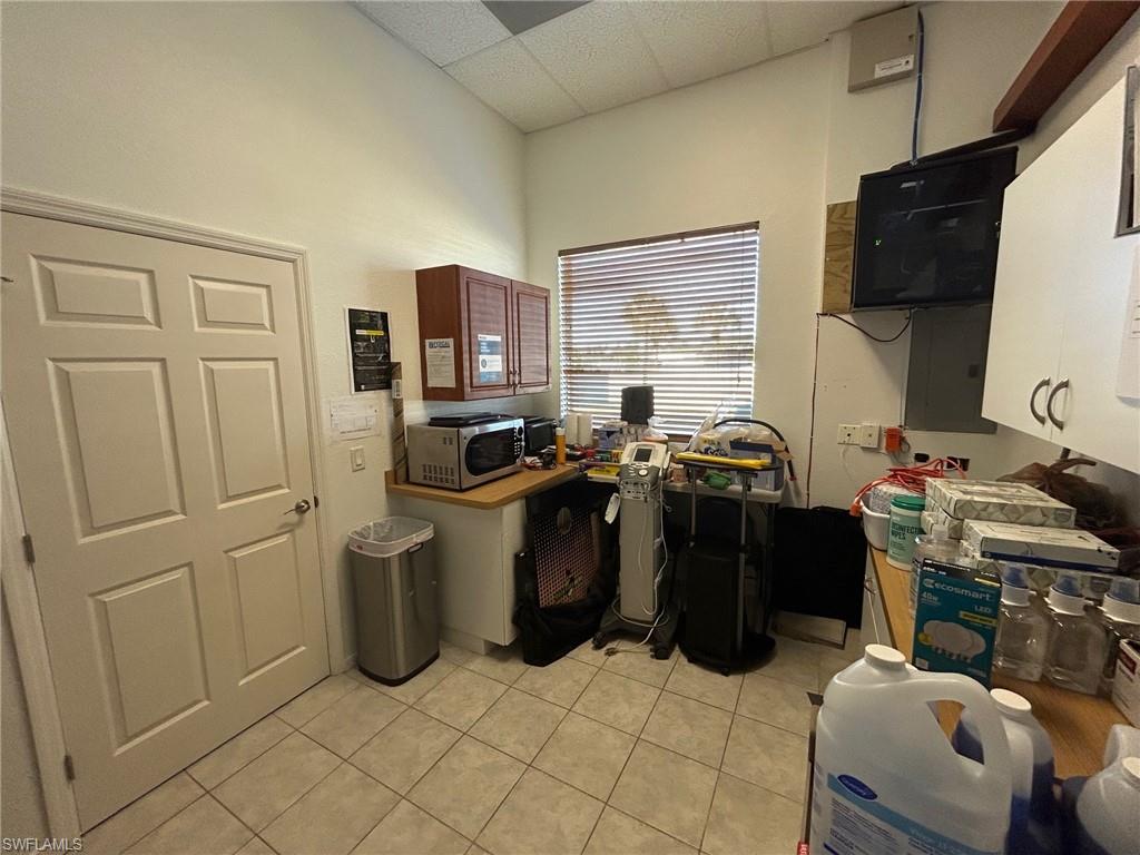 Kitchen featuring light tile patterned floors, a paneled ceiling, electric panel, and stainless steel microwave