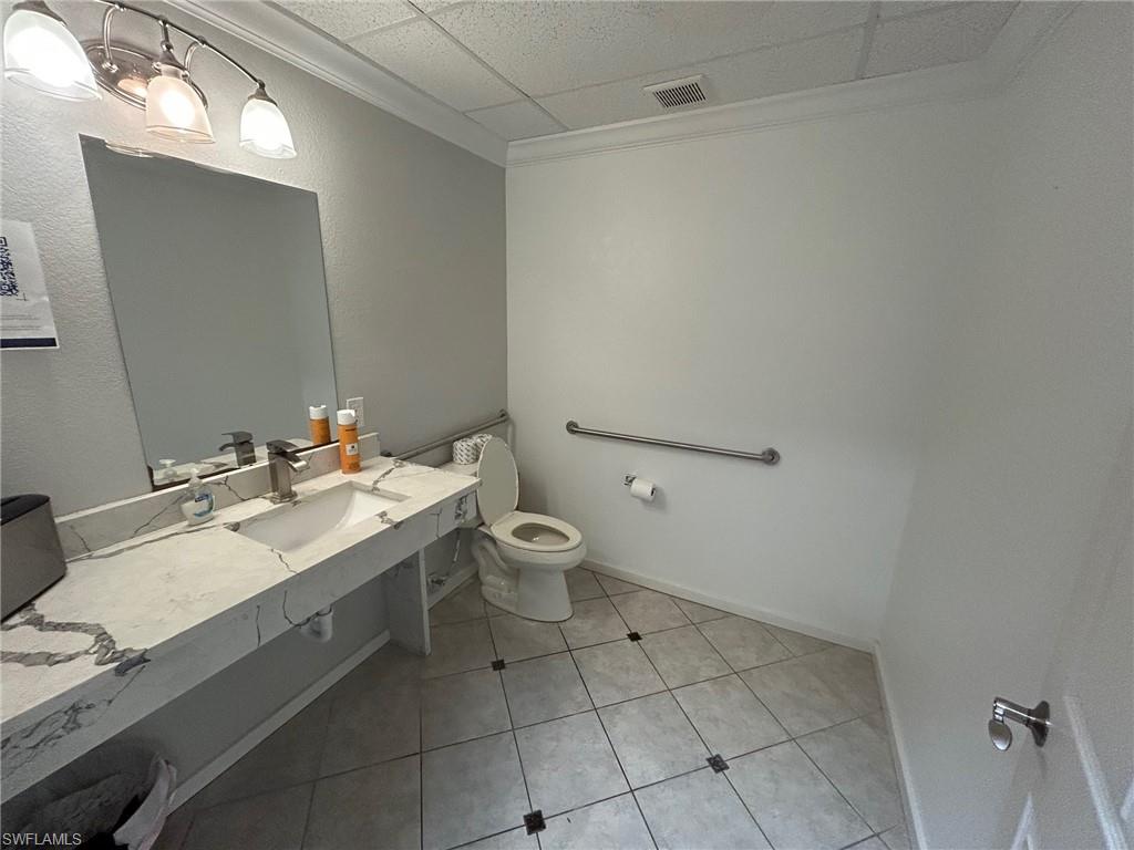 Bathroom with ornamental molding, vanity, light tile patterned flooring, and a drop ceiling