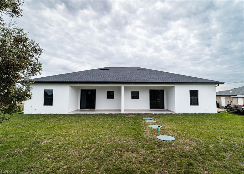 Back of house featuring a patio area, stucco siding, and a lawn