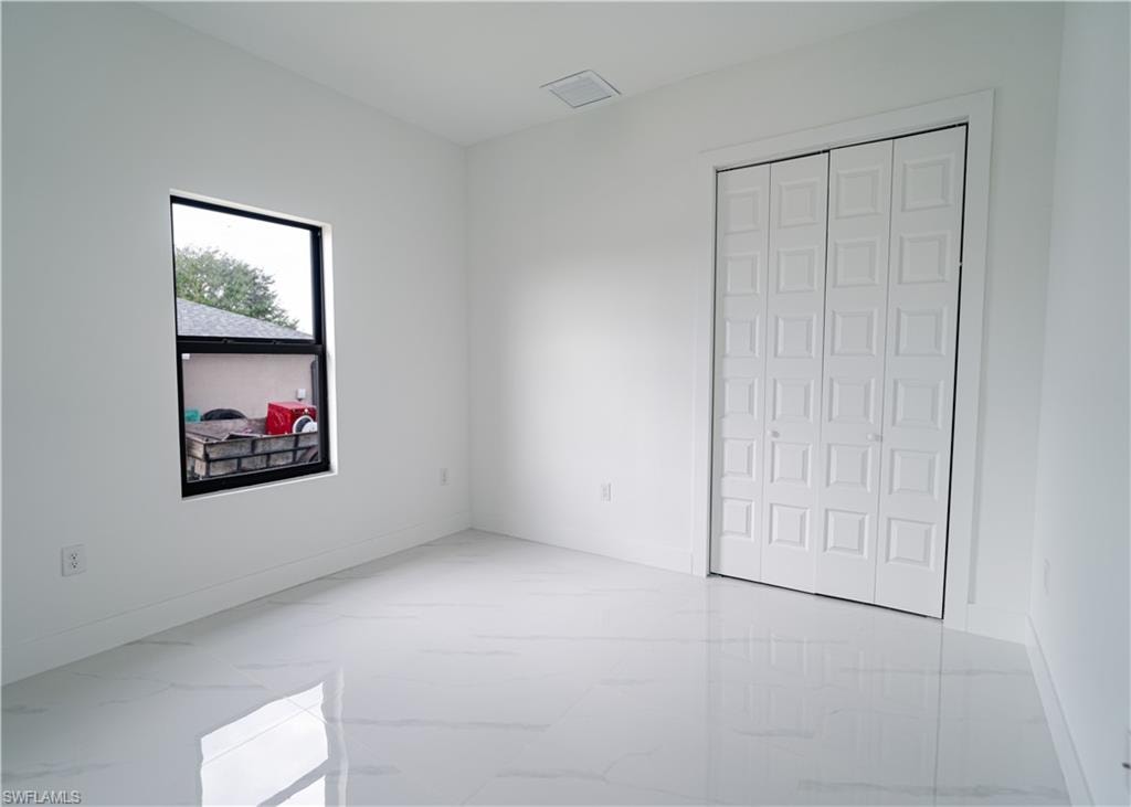 Unfurnished bedroom with light marble finish floors and a closet