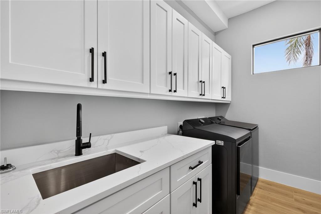 Washroom featuring light wood-type flooring, cabinet space, and independent washer and dryer