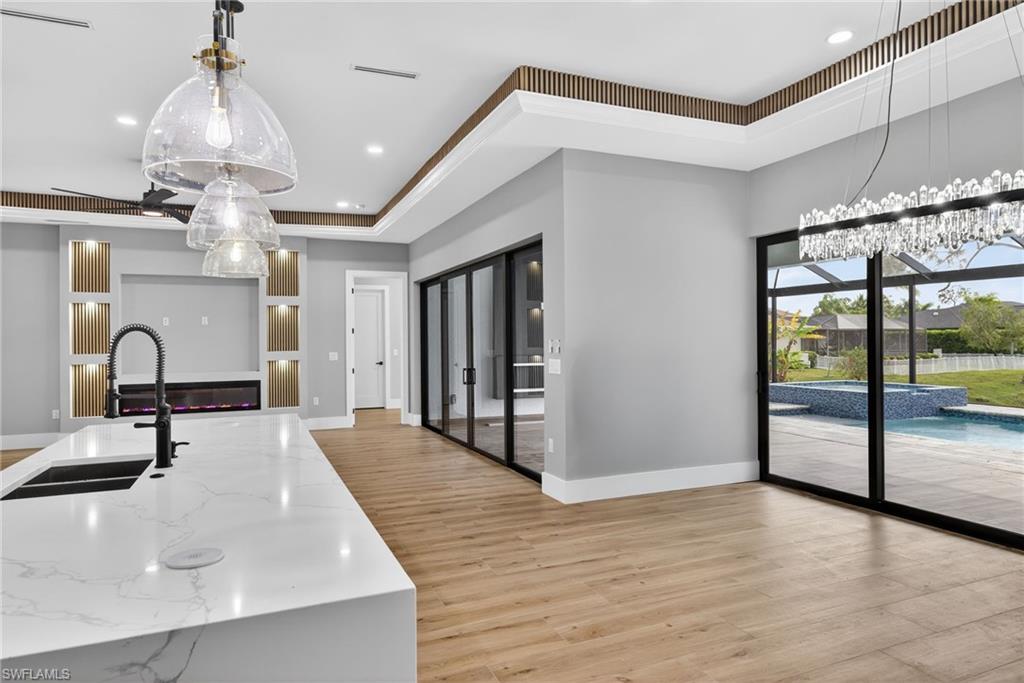 Kitchen with pendant lighting, light stone countertops, a center island with sink, light wood finished floors, and recessed lighting