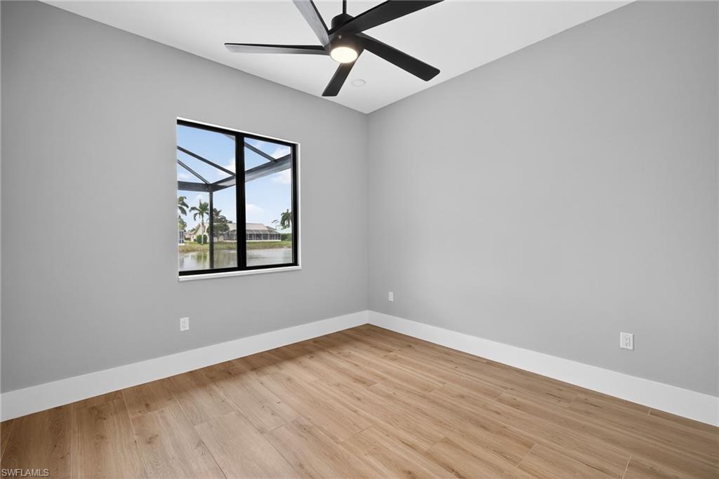 Empty room featuring a water view, light wood finished floors, and a ceiling fan