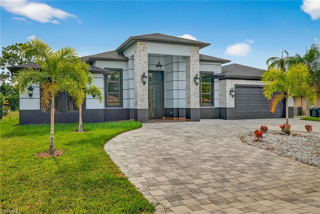 View of front facade featuring decorative driveway, a front lawn, a garage, and stucco siding
