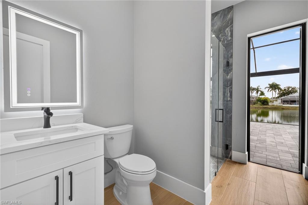 Full bath with vanity, a marble finish shower, light wood-style floors, and a water view