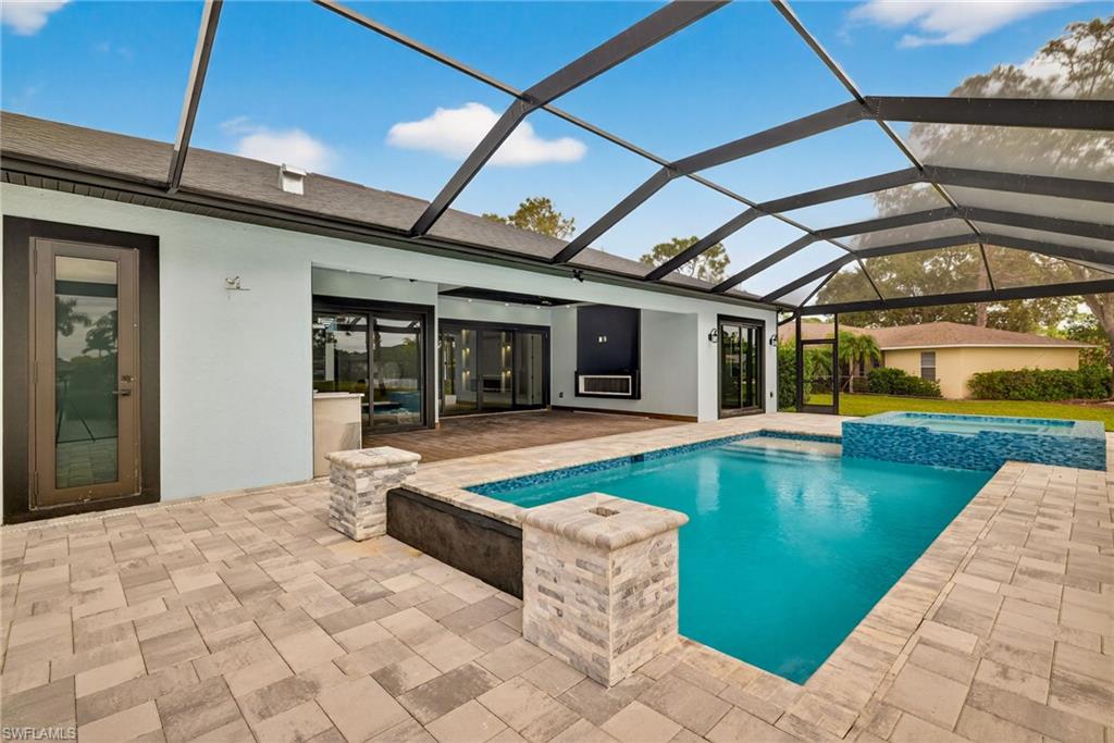 View of swimming pool featuring a sunroom, a pool with connected hot tub, a lanai, and a patio
