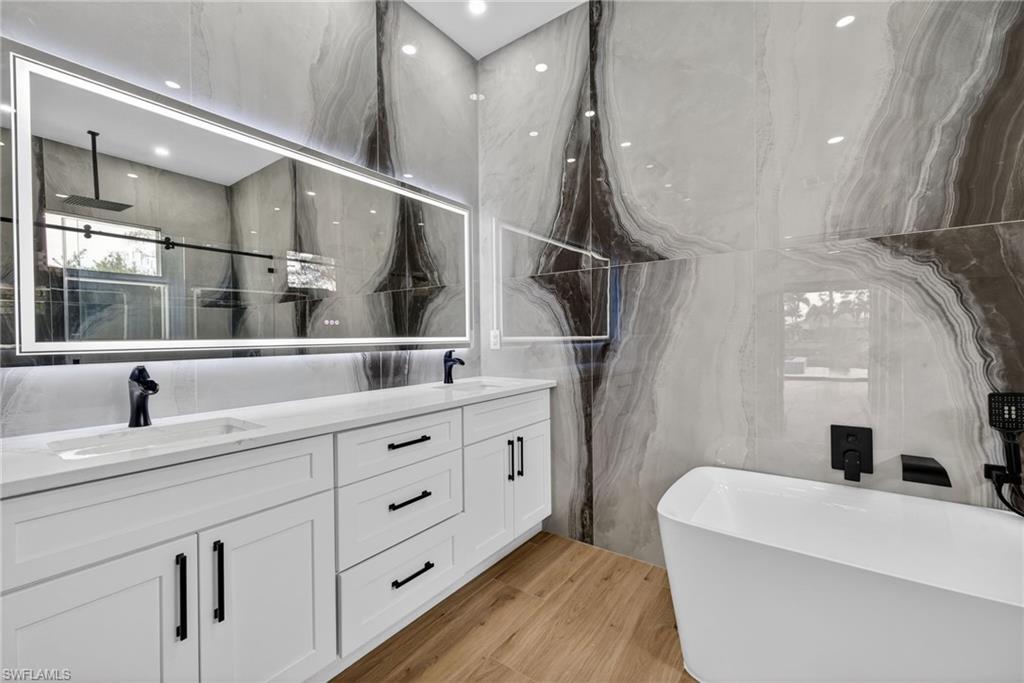 Primary bath featuring a freestanding bath, double vanity, and a shower with shower door
