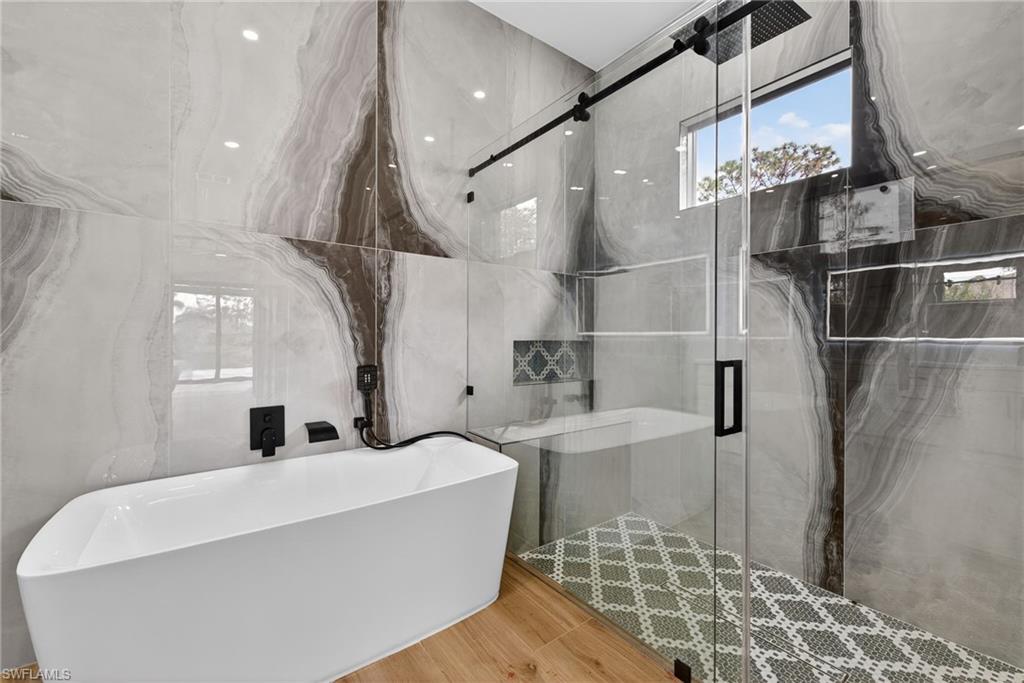 Primary bath with a freestanding tub and a marble finish shower