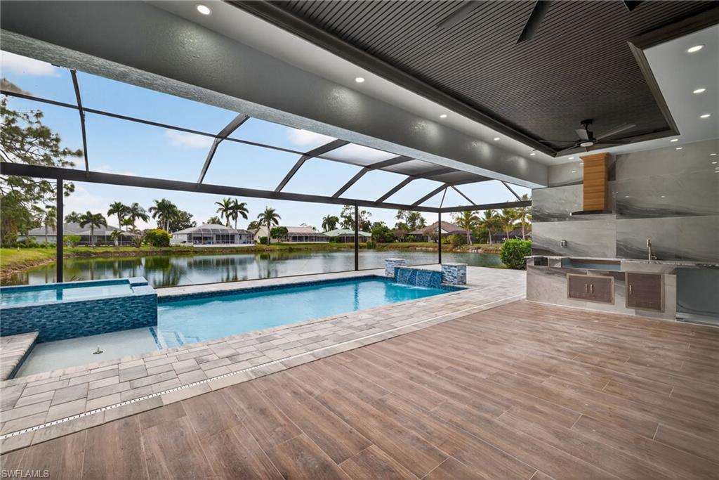 View of pool with a lanai, an outdoor kitchen, a water view, and a sunroom