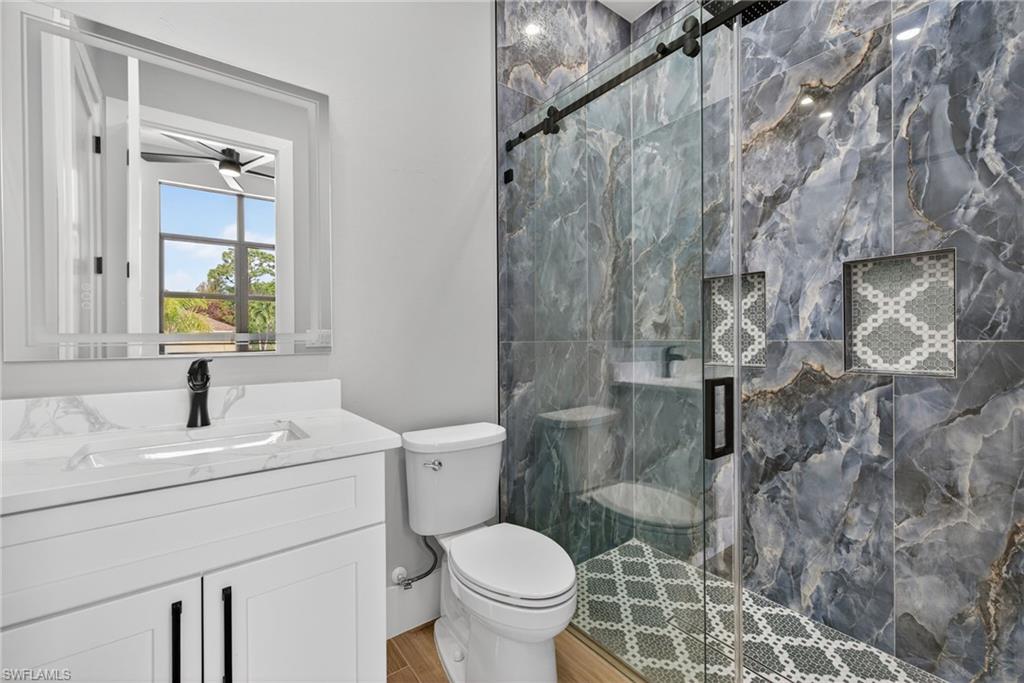 Full bath featuring a marble finish shower, vanity, and a ceiling fan