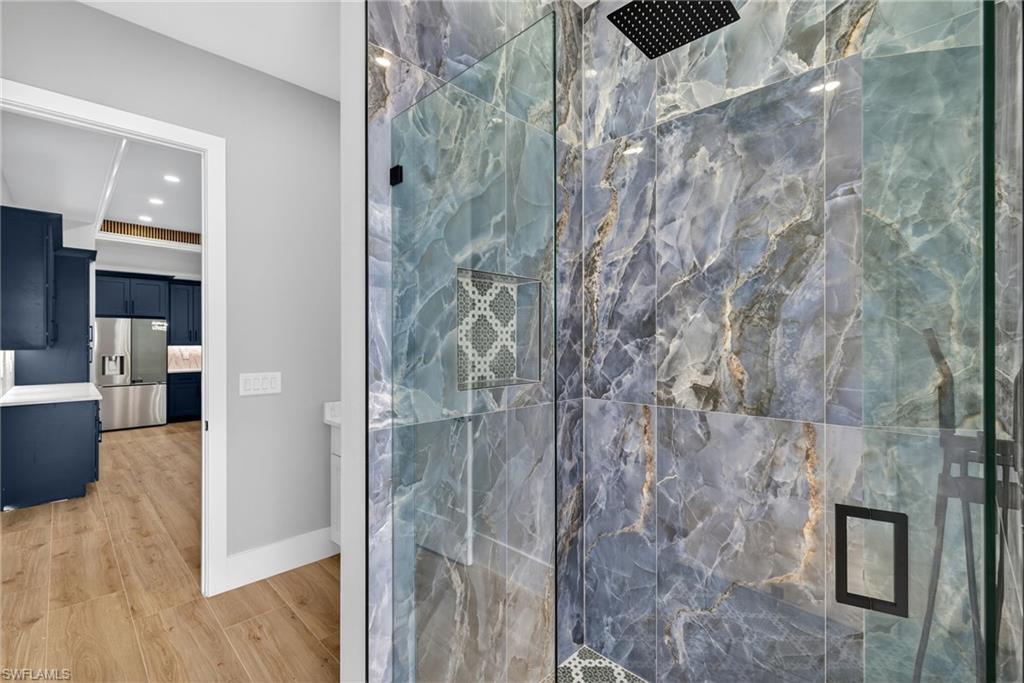 Ensuite bathroom with a marble finish shower, light wood-style floors, and recessed lighting