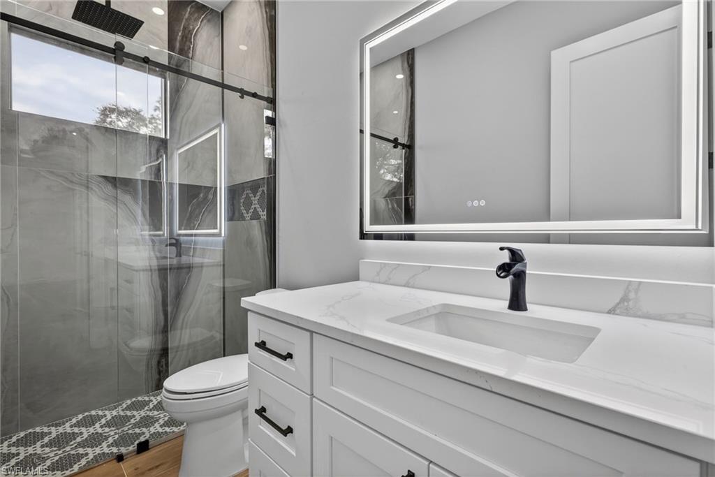 Full bathroom featuring a marble finish shower and vanity