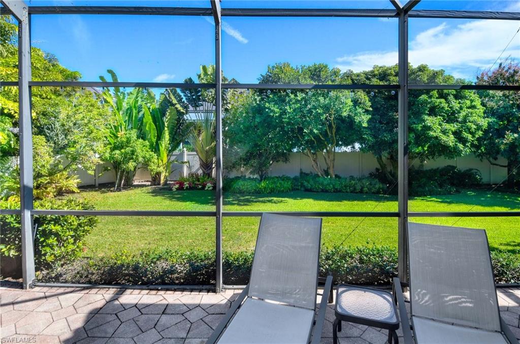 Fenced backyard featuring a sunroom and glass enclosure