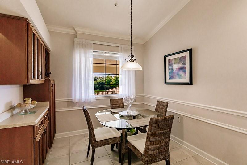 Dining space with lofted ceiling, light tile patterned floors, and ornamental molding