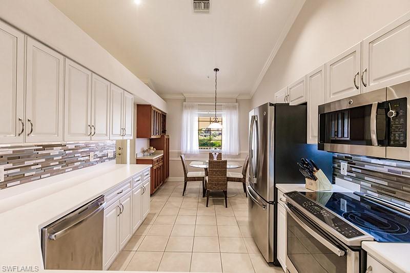 Kitchen with white cabinetry, tasteful backsplash, hanging light fixtures, vaulted ceiling, and appliances with stainless steel finishes