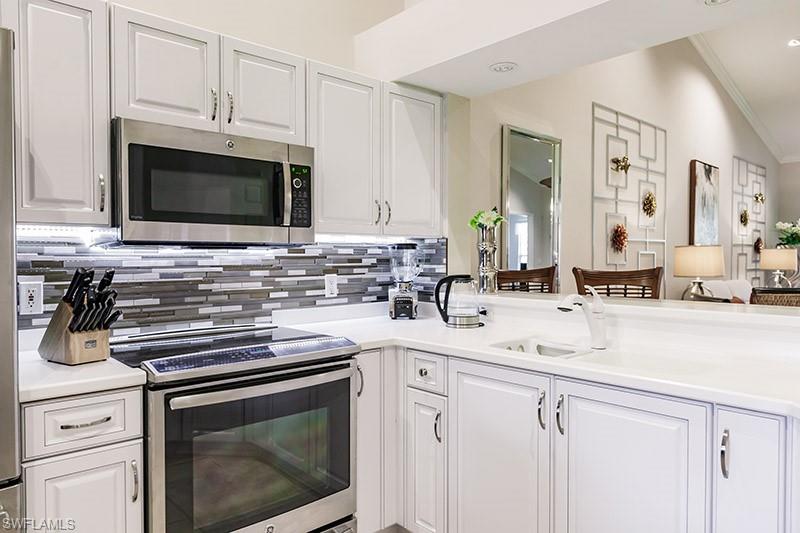 Kitchen featuring white cabinetry, crown molding, appliances with stainless steel finishes, vaulted ceiling, and sink