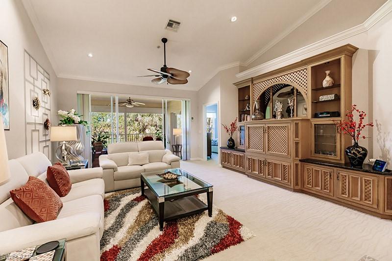 Carpeted living room with ornamental molding, ceiling fan, and vaulted ceiling