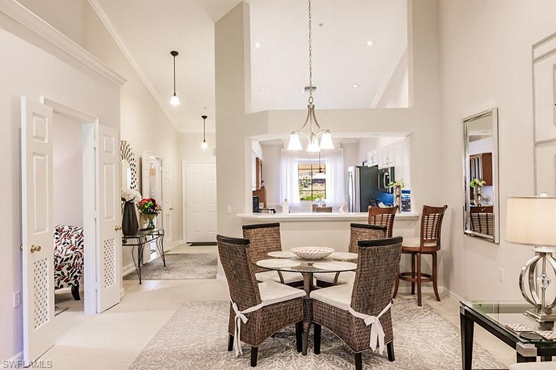 Carpeted dining area featuring ornamental molding and high vaulted ceiling