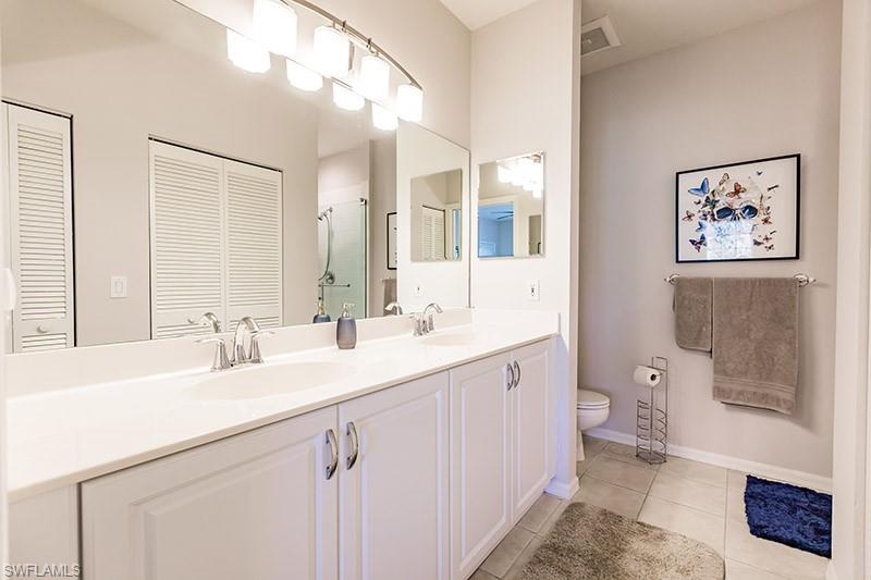 Bathroom featuring tile patterned floors, toilet, and dual bowl vanity