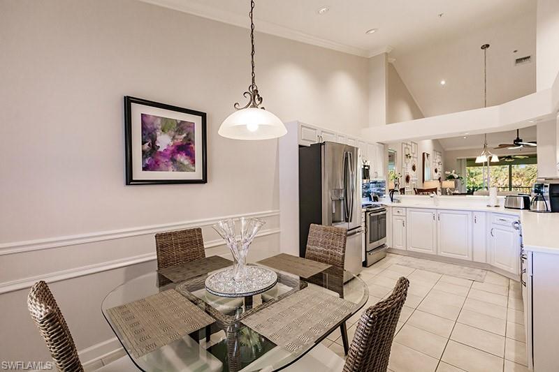 Tiled dining room featuring high vaulted ceiling, crown molding, and ceiling fan