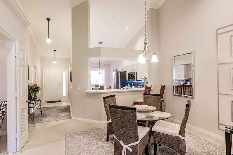 Dining space featuring light tile patterned flooring, ornamental molding, and high vaulted ceiling