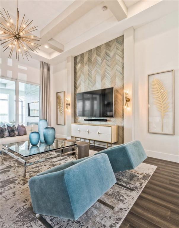 Living area featuring dark wood finished floors, an accent wall, beam ceiling, coffered ceiling, and a chandelier