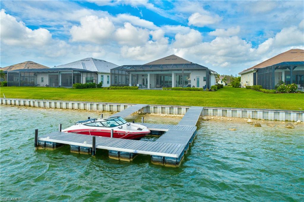 Dock featuring a sunroom, a water view, a lawn, and a lanai