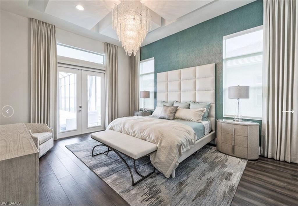 Bedroom featuring french doors, access to exterior, dark wood finished floors, and a chandelier