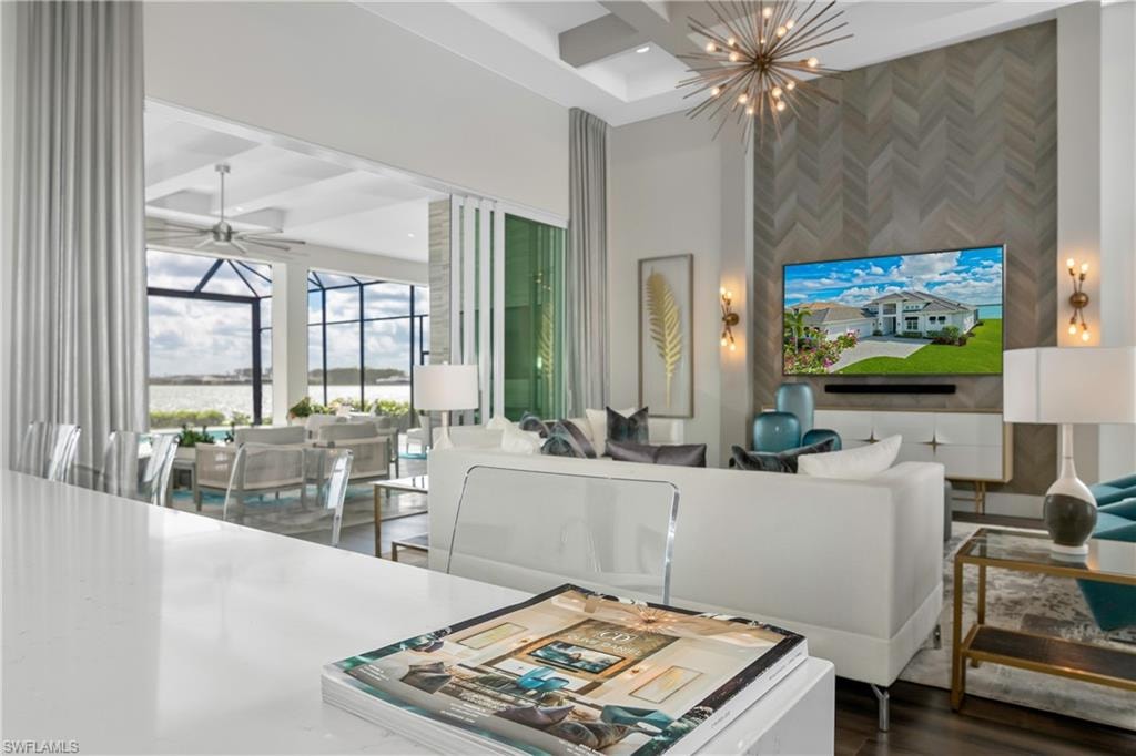 Living area featuring an accent wall, a ceiling fan, coffered ceiling, a towering ceiling, and a chandelier